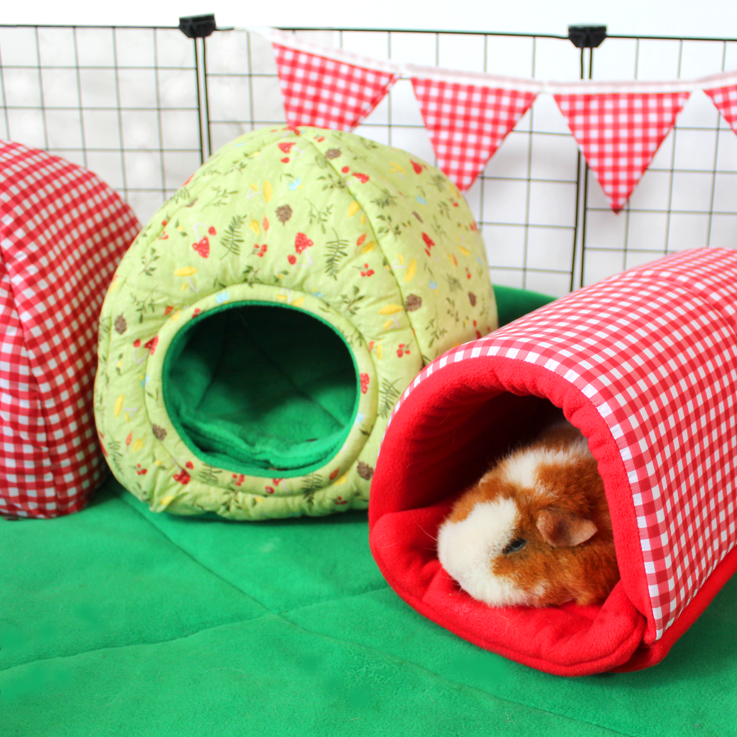 Red Gingham Snuggle Tunnel, inside a cage set up with a sleepy guinea pig relaxing inside the tunnel