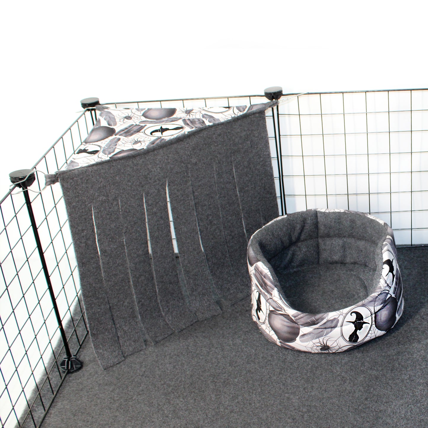 Pet crate with a gray cover and matching bed inside, featuring a pattern of black shapes on a white background.