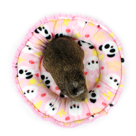Small animal on a pink circular mat with panda patterns