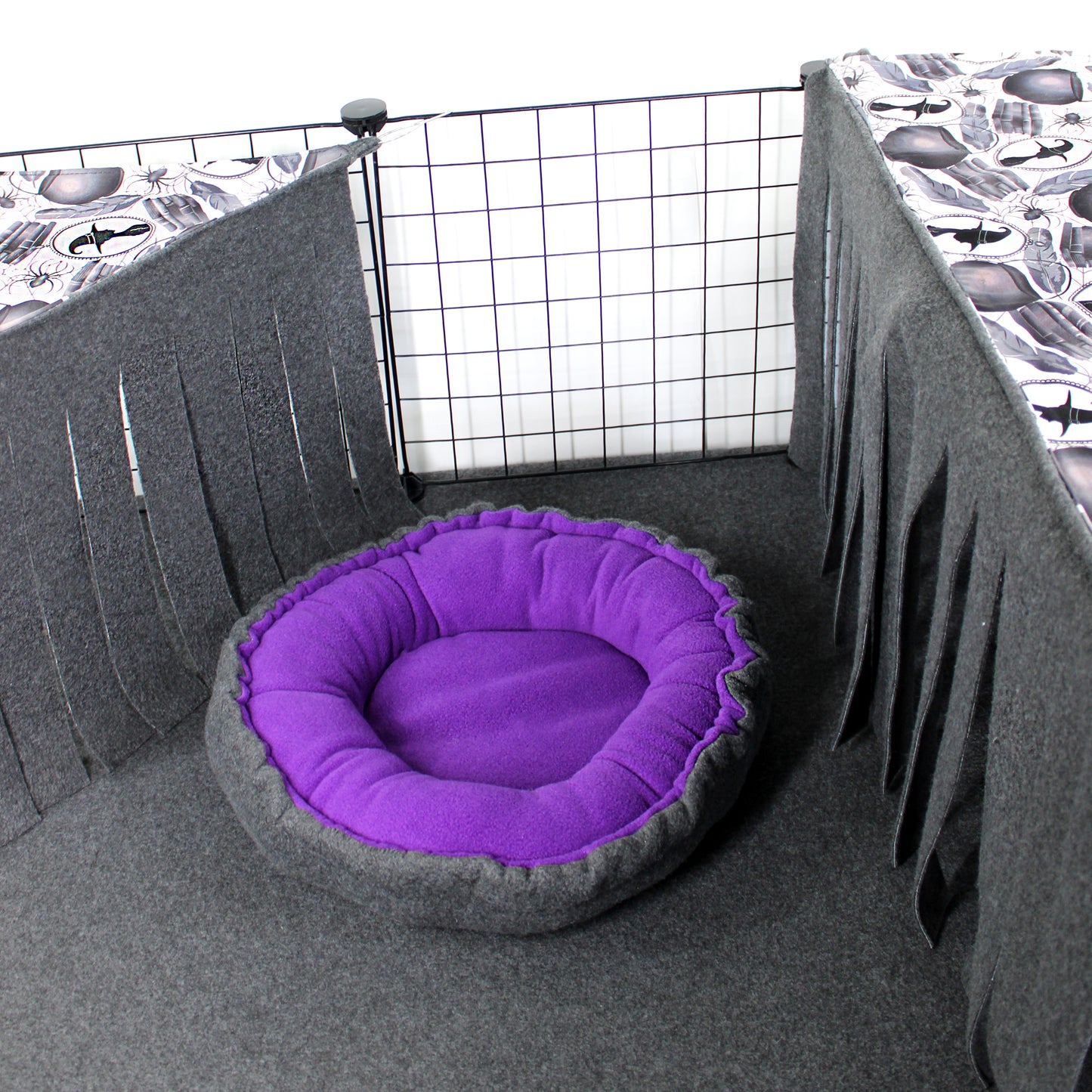 Purple and gray pet bed inside a wire cage with patterned walls.