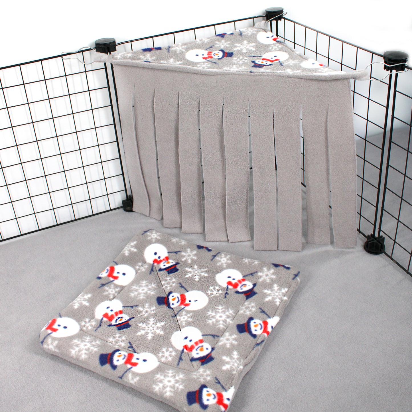 Baby crib with snowman and snowflake patterned sheet and gray curtain.