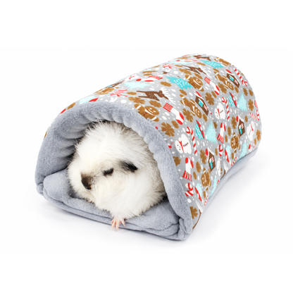 Fluffy white guinea pig relaxing inside a handmade grey gingerbread Christmas tunnel with a soft grey fleece interior