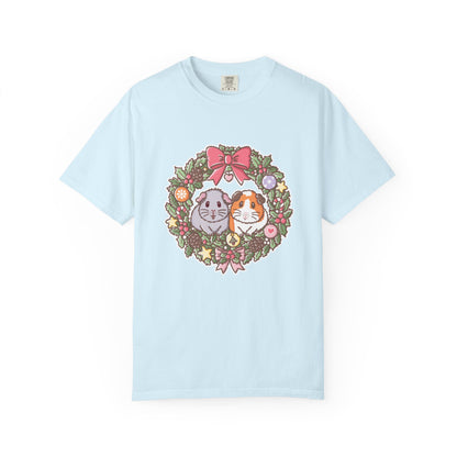 Light blue Christmas T-shirt featuring a festive guinea pig wreath illustration.