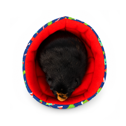 Top-down view of a blue Christmas guinea pig cuddle cup with a bright festive print and soft red anti-pill fleece lining