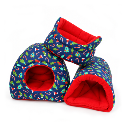 Matching blue Christmas novelty guinea pig accessory bundle featuring a cuddle cup, hidey house and snuggle tunnel, all made with festive blue cotton decorated with Christmas trees, stockings, candy canes, holly and Santa hats, paired with bright red anti-pill fleece linings.