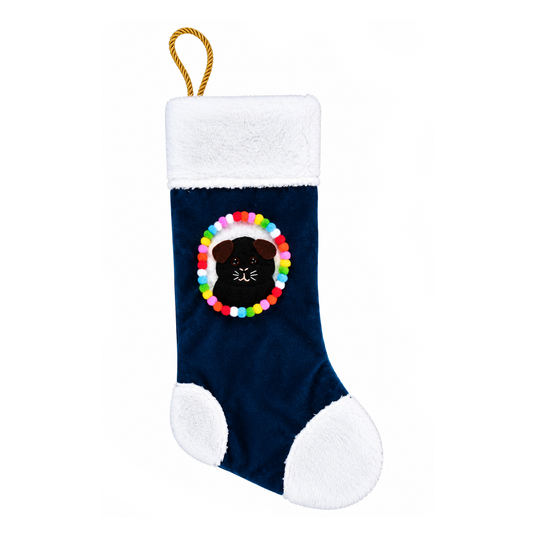 Black guinea pig Christmas stocking with brown felt ears, colourful pom-pom border, white fleece trim and gold rope hanging loop on navy blue velvet.