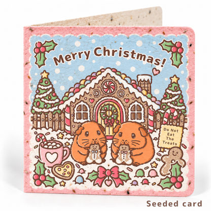 Seeded Christmas guinea pig card featuring Jaffa Orange and Gingercake outside a festive gingerbread house, with visible seeds in the paper