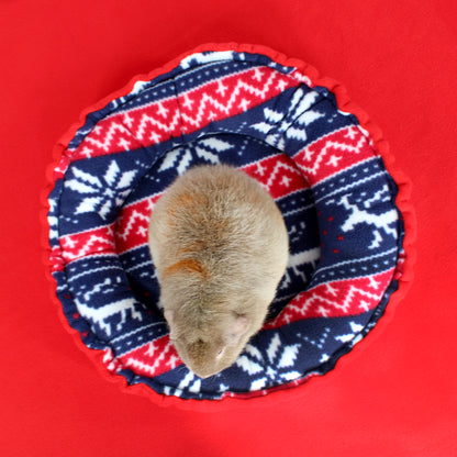 Small animal inside a circular fabric cozy with red, blue, and white pattern on a red background