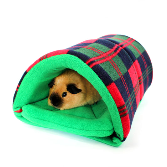 Small animal peeking out from a green and red plaid pet bed on a white background
