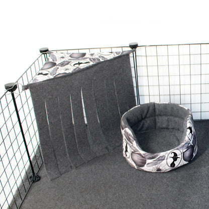 Pet crate with a gray cover and matching bed inside, featuring a pattern of black shapes on a white background.