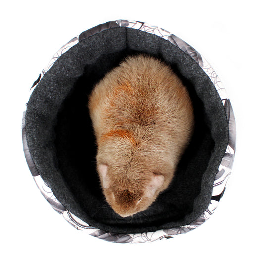 Small animal, possibly a hamster, curled up inside a dark gray pet bed on a white background