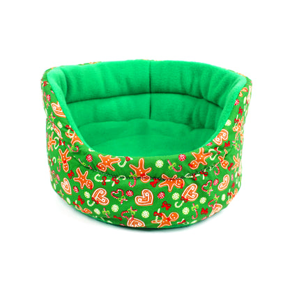 Green pet bed with festive gingerbread pattern on a white background