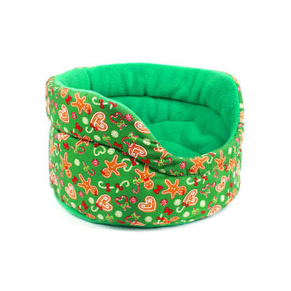 Green pet bed with festive gingerbread design on a white background