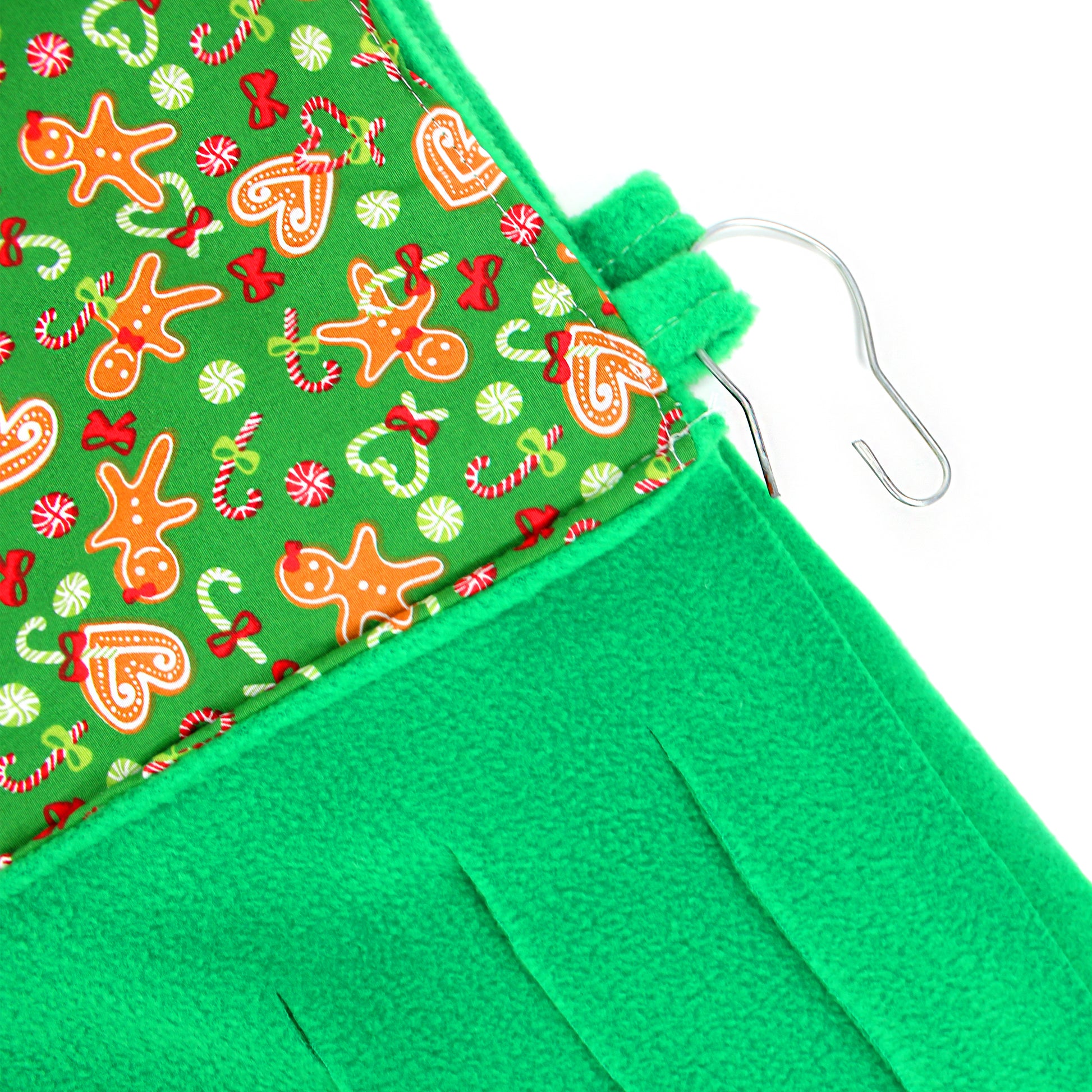 Green fabric with Christmas-themed pattern and a hanger on a white background