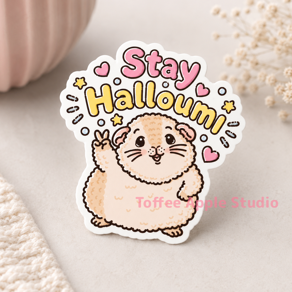 Stay Halloumi guinea pig sticker on a cosy fabric surface