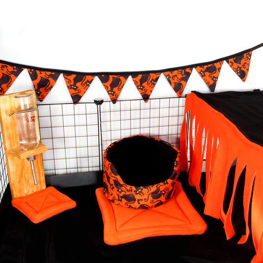 Halloween Black Cat Cuddle Cup Bed, inside a cage with a few other Halloween products