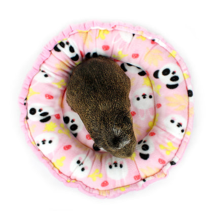 Small animal on a pink circular mat with panda patterns