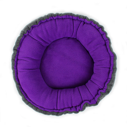Round pet bed with purple interior and gray exterior on a white background