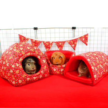 Three guinea pigs in red floral pet houses with a white background