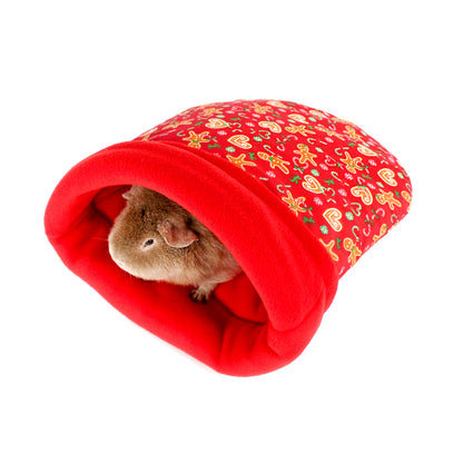Small animal peeking out from a red fleece tunnel with gingerbread men pattern on a white background