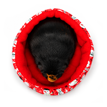 Top-down view of Olive sitting in a red snowman print cuddle cup with a cosy red fleece lining