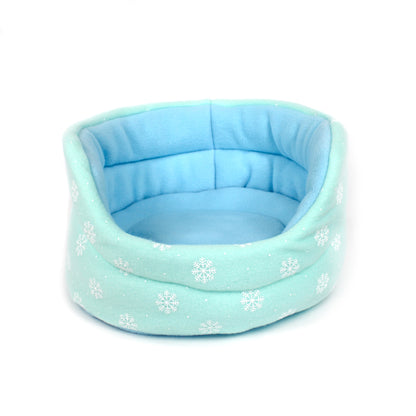 Light blue pet bed with snowflake pattern on a white background