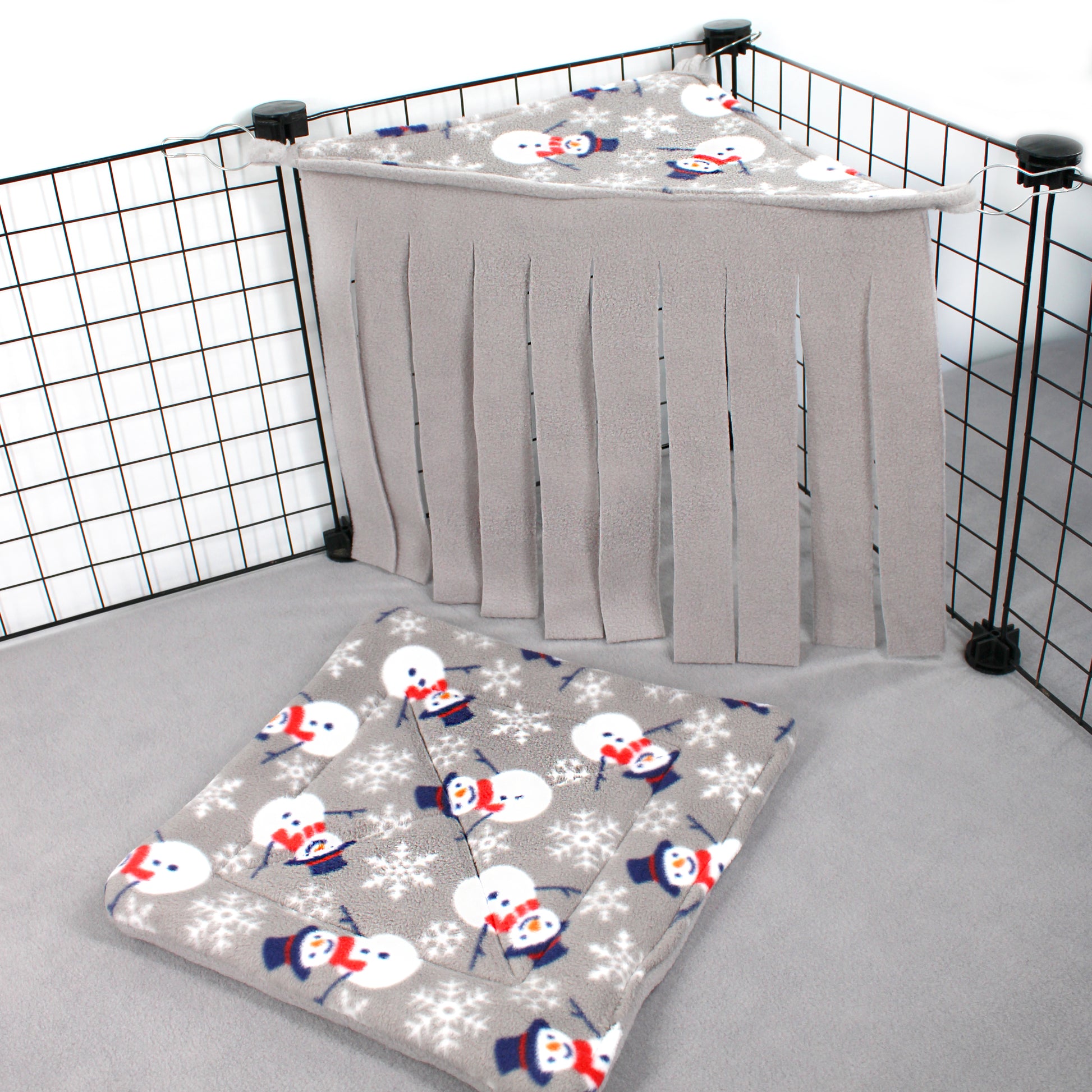 Baby crib with snowman and snowflake patterned sheet and gray curtain.