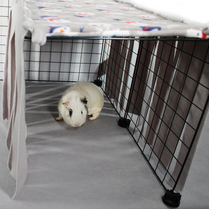 Guinea pig inside a wire cage with a colorful blanket on top