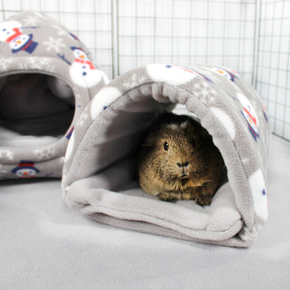 Guinea pig peeking out from a gray fleece tunnel with colorful snowman pattern in a pet enclosure.