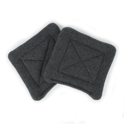 Two dark gray square coasters with a geometric pattern on a white background