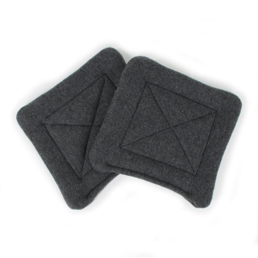 Two dark gray square pee pads with a geometric pattern on a white background
