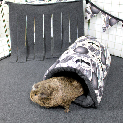 Guinea pig peeking out from a patterned tunnel in a pet enclosure.